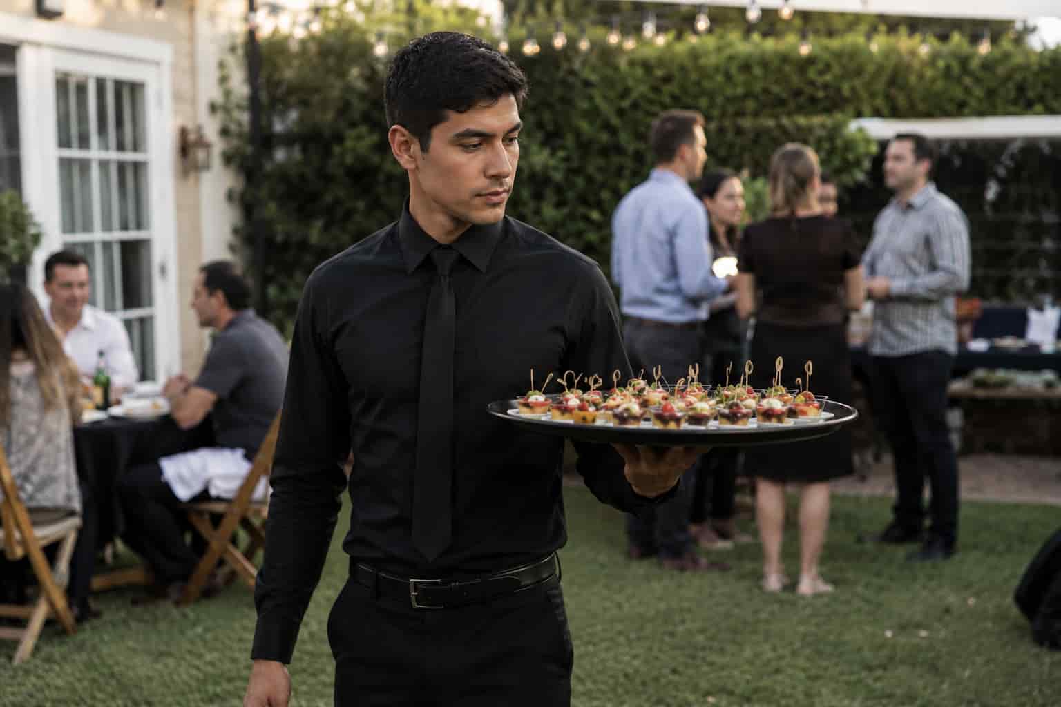 Event waiter providing tray pass service during cocktail hour at a private event