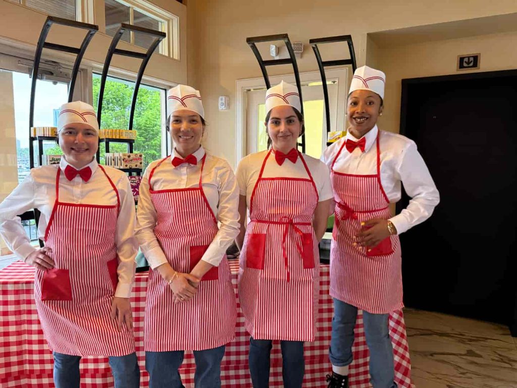 Catering team in red bow ties and aprons standing in front of a snack station