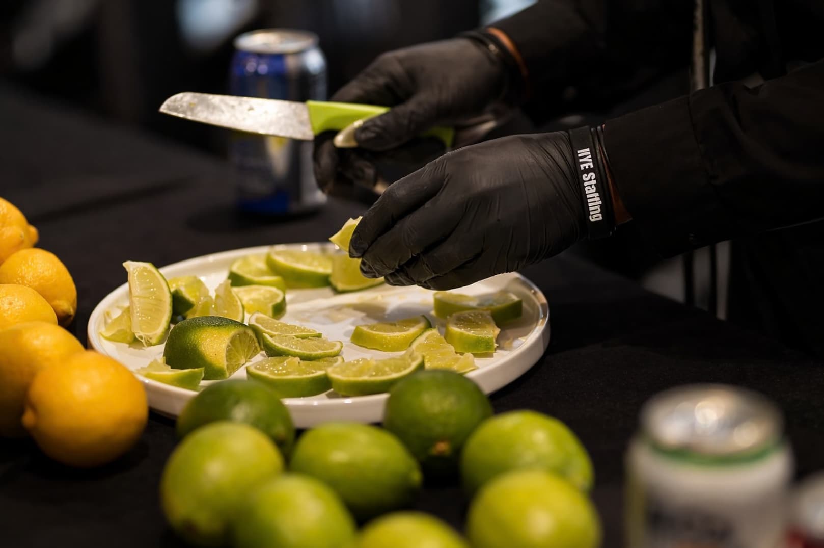 Bartender preparing fresh cocktail garnishes by cutting limes and lemons for drinks at an event bar setup in Boston